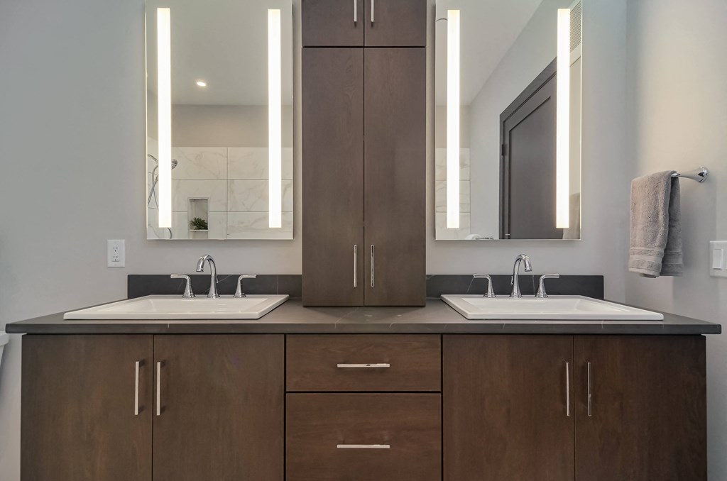 a bathroom with two sinks and a cabinet with two mirrors