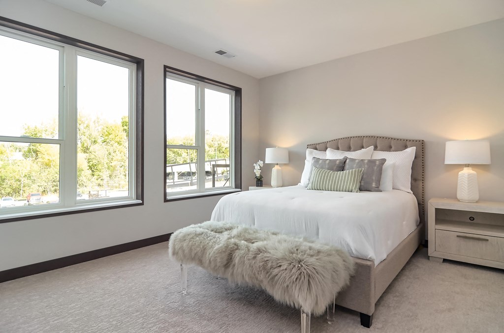 the master bedroom has a large bed and large windows