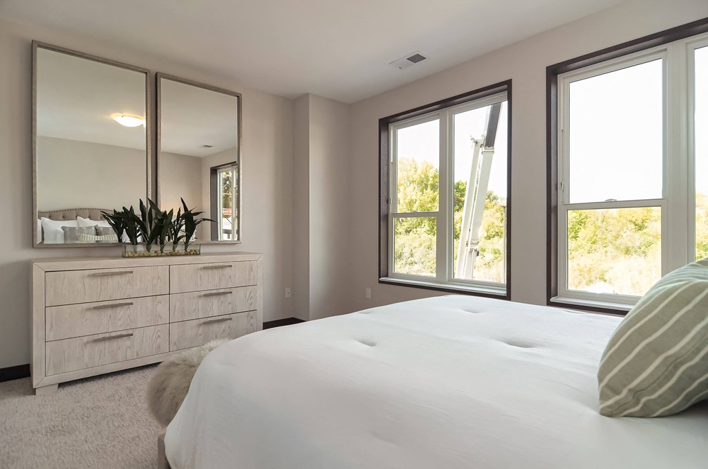 the master bedroom has large windows and a large white bed