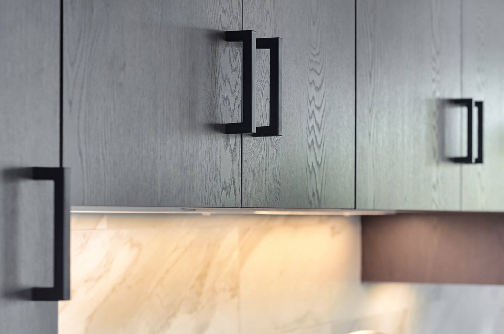 a close up of a kitchen cabinet with black handles