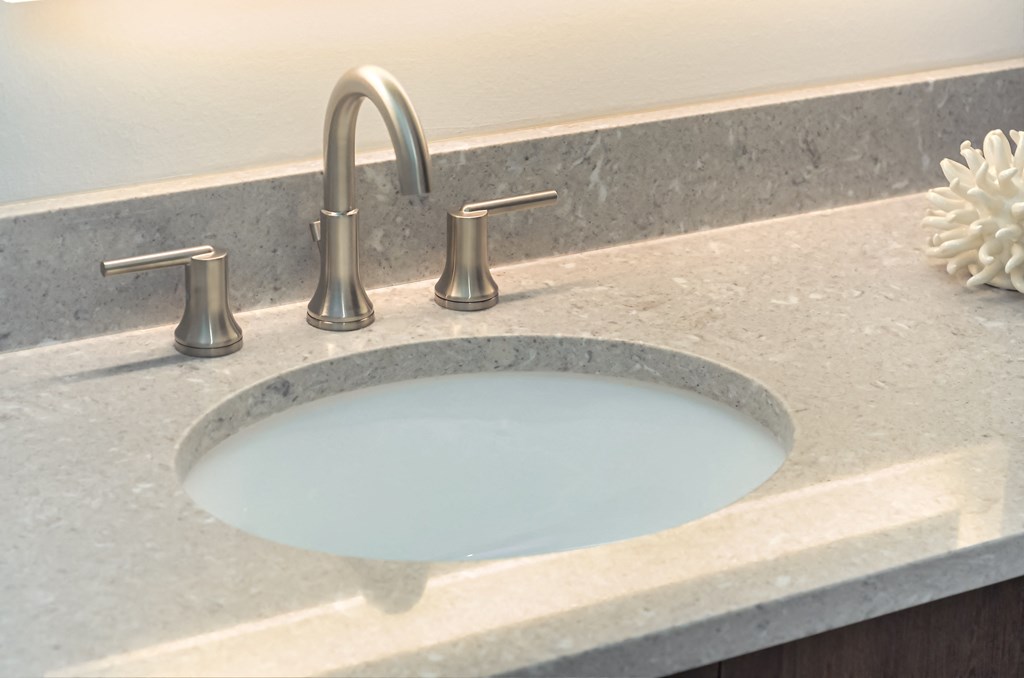 a sink with a faucet on a counter top with a marble counter top