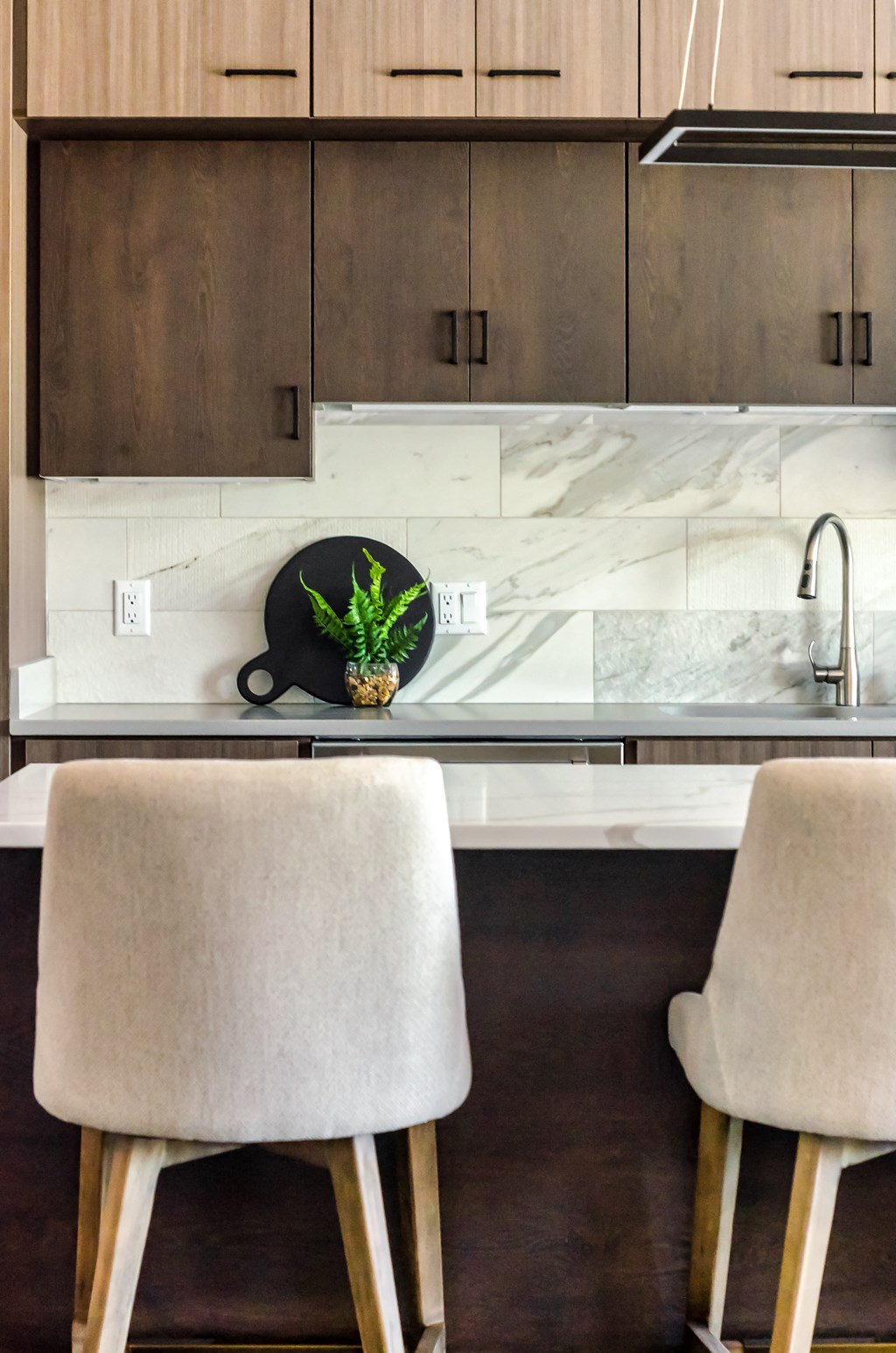 a kitchen counter with two chairs and a sink