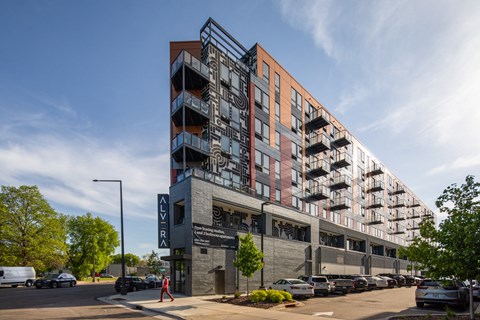 a large building with many balconies and cars parked on the street