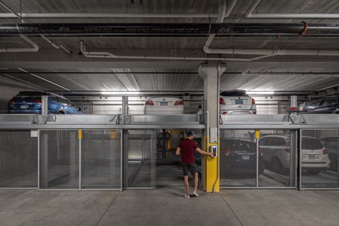 a man standing at a parking meter in a parking garage
