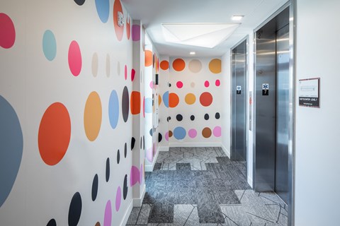 a hallway with colourful dots on the wall and a door