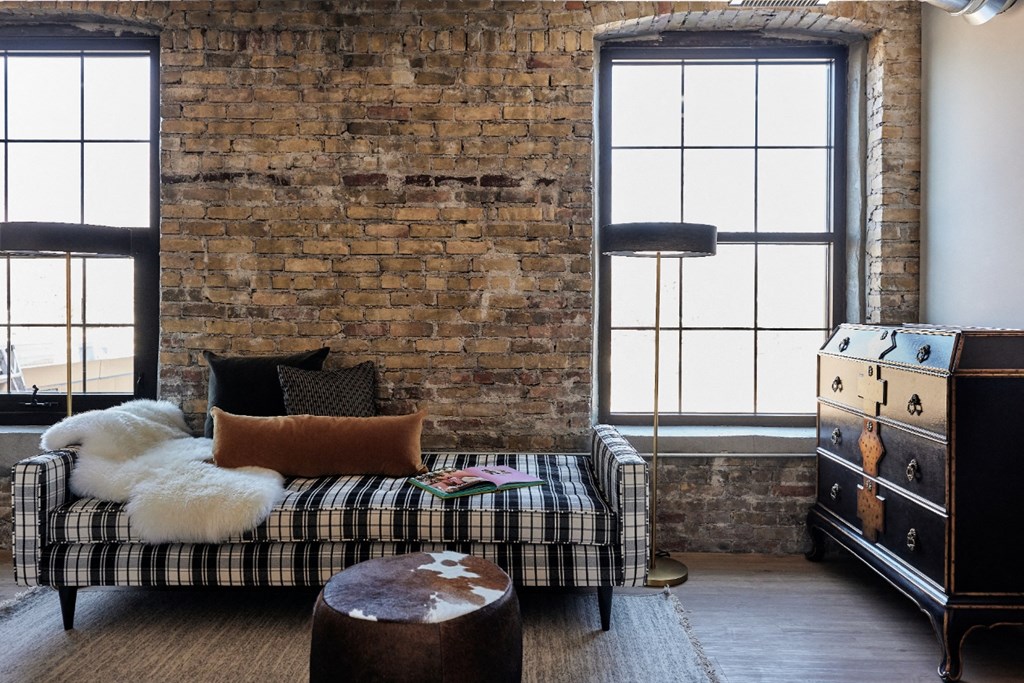 an exposed brick wall in a living room with a couch and a dresser
