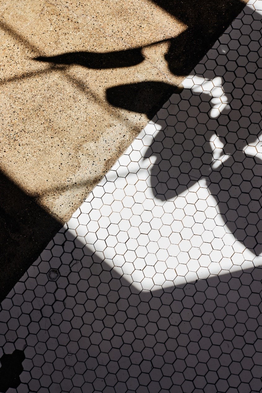 a shadow of a person on a floor with hexagonal tiles