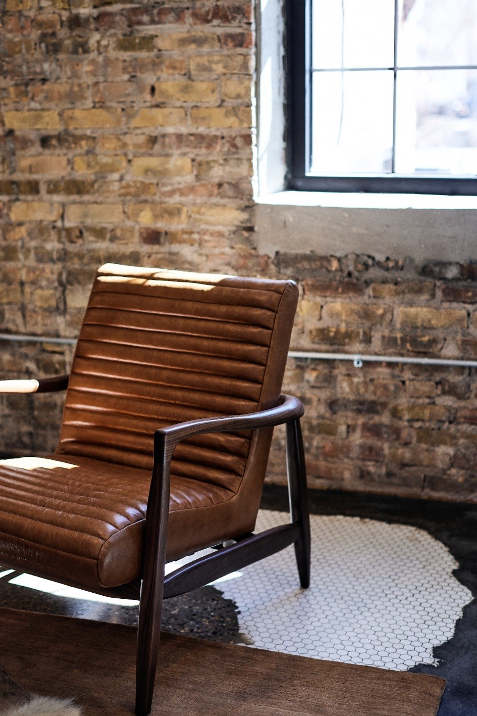 a leather chair in front of a brick wall