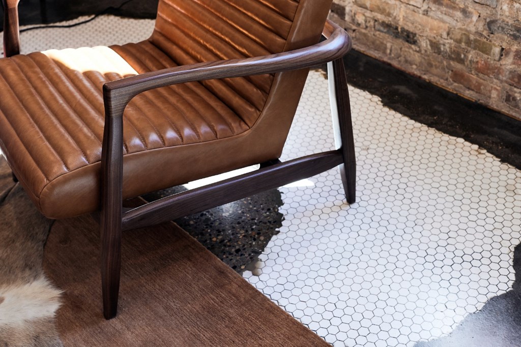 a brown leather chair sitting on top of a tiled floor