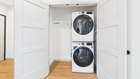 Two white front loading washing machines in a small laundry room.