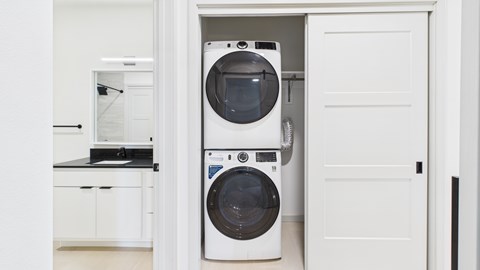 A white washing machine is in a small cabinet in a kitchen.