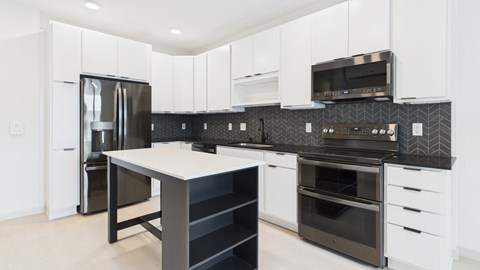 A modern kitchen with black and white appliances and cabinets.
