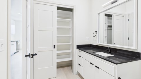 A white kitchen with a black countertop and a white fridge.