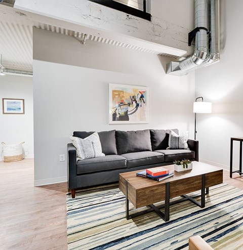 A living room with a grey couch and a wooden coffee table.