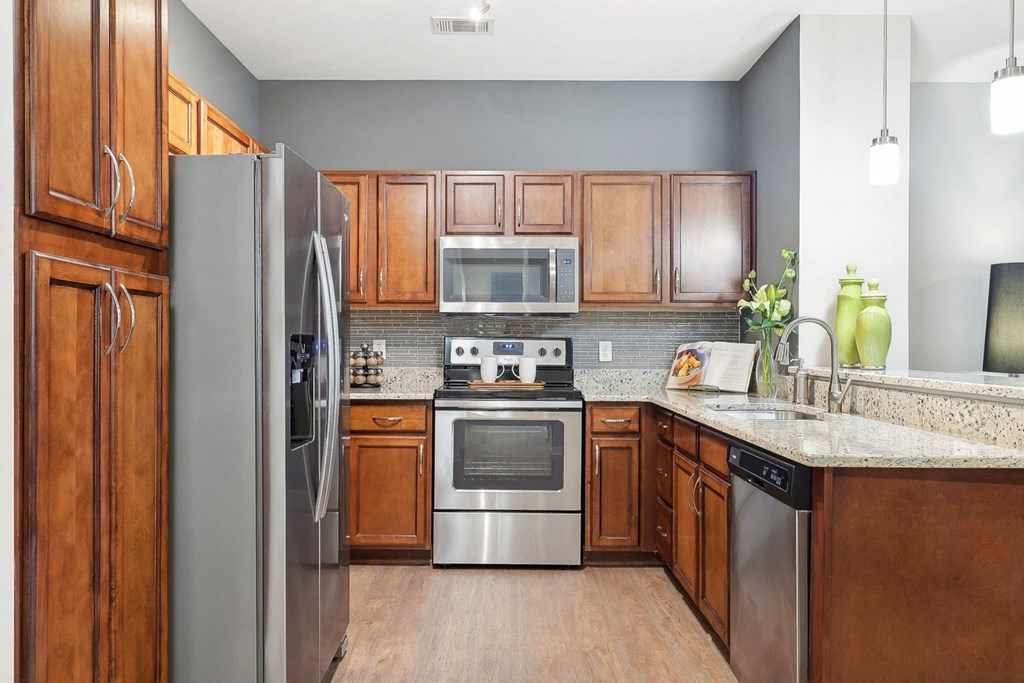 spacious kitchen with stainless appliances and custom maple-stained cabinetry at Sorelle apartments