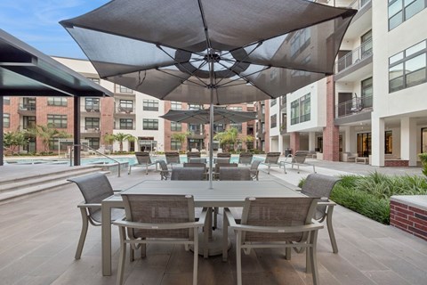 A patio with a table and chairs under umbrellas.
