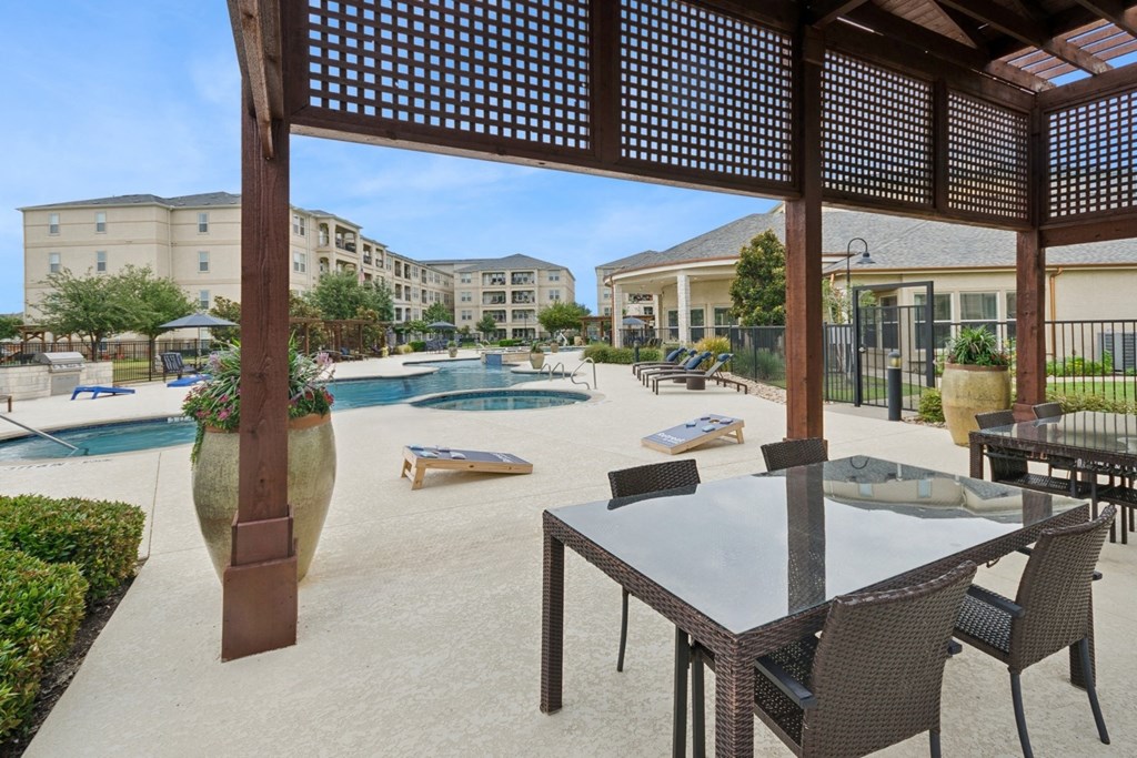 outdoor patio with corn hole game and shaded dining area at Retreat at Wylie senior 55+ apartments