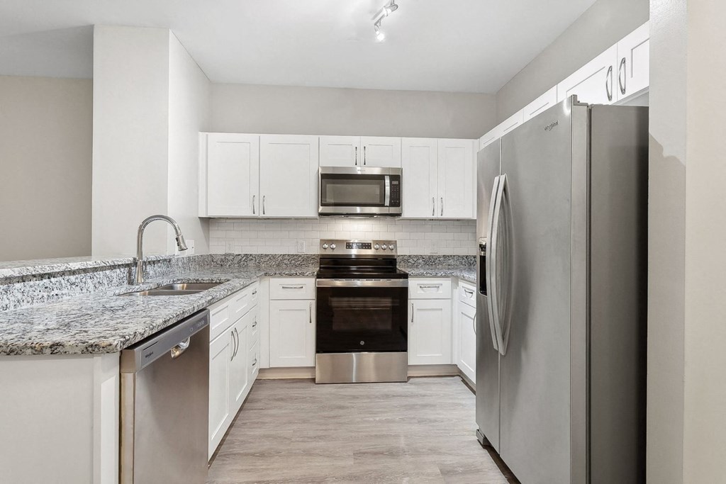 kitchen with custom white cabinetry, granite countertops, and stainless steel appliances at Sorelle apartments