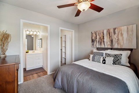 A bedroom with a bed, dresser, mirror and a ceiling fan.