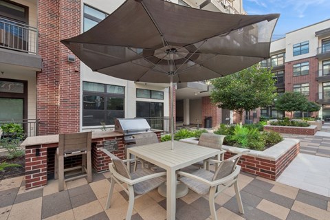 A patio with a table and chairs under an umbrella.