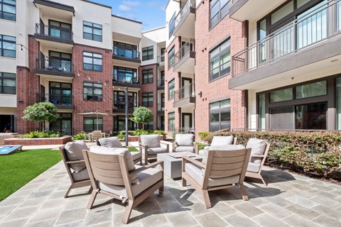 A patio with chairs and a table in front of apartment buildings.