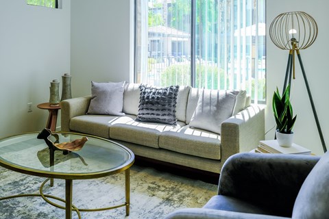 A living room with a white couch and a glass table.
