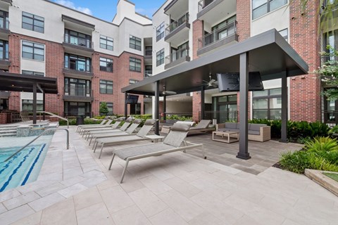 A pool area with sun loungers and a building in the background.