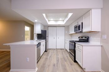 a kitchen with white cabinets and a wooden floor