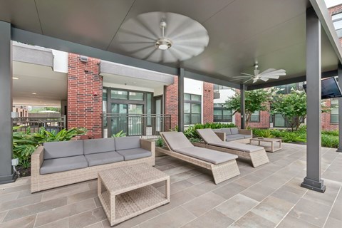 A patio with a grey sofa, a wooden coffee table and a white umbrella.