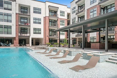 A swimming pool with lounge chairs and a building in the background.