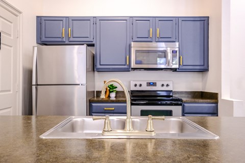 A kitchen with a stainless steel refrigerator and a double sink.