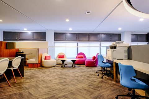 A modern office space with a variety of seating options and a carpeted floor.