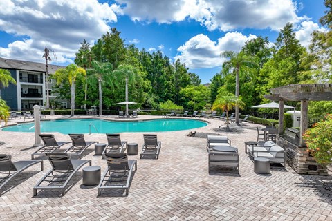 a swimming pool with tanning chairs at Verano apartments