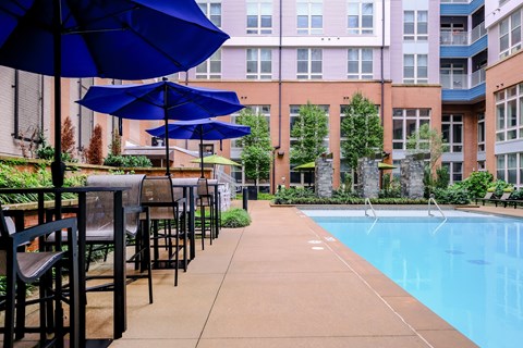 A pool area with chairs and umbrellas.