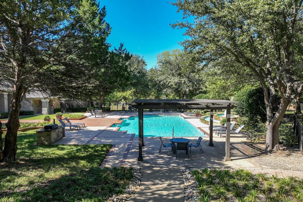 a resort-inspired swimming pool surrounded by lush landscaping at Stoneleigh on Spring Creek apartments