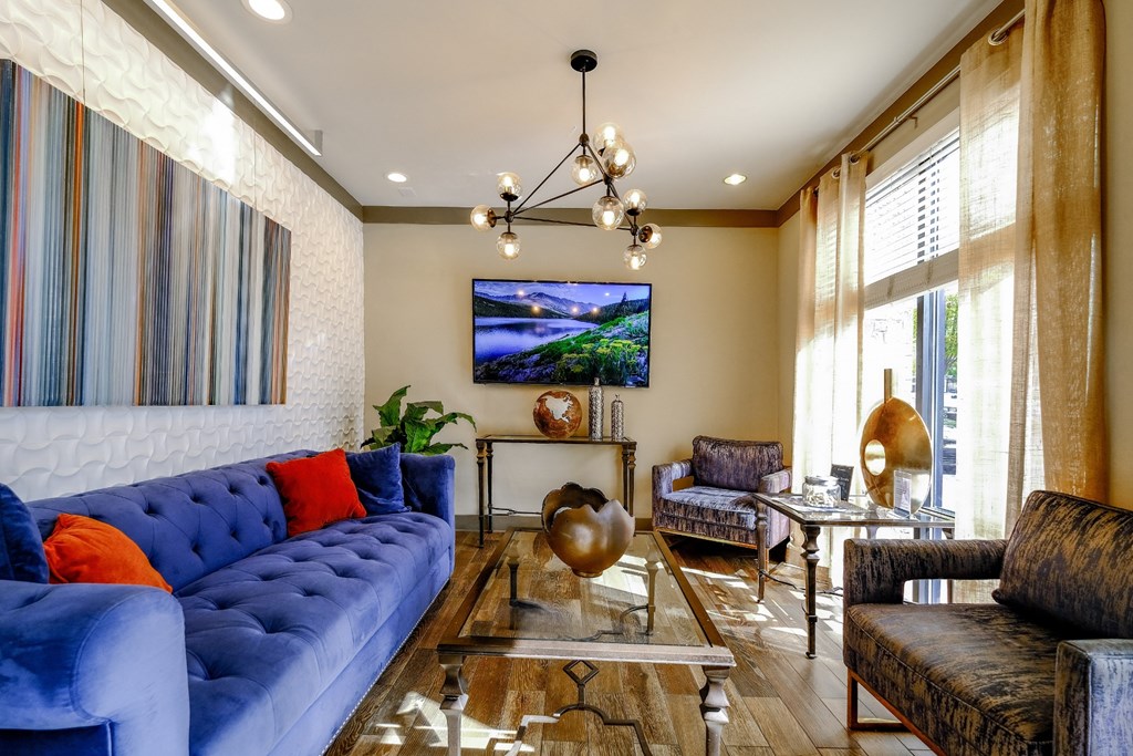 a living room with blue couches and chairs and a glass table