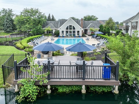 A pool area with a deck and umbrellas.
