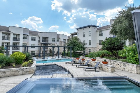resort-style swimming pool with sun deck lounging areas at The Allure apartments