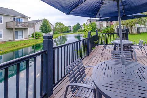 A patio with a table and chairs overlooking a lake.