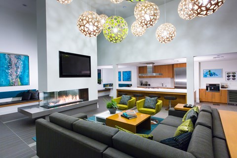 A modern living room with a grey couch and a fireplace.