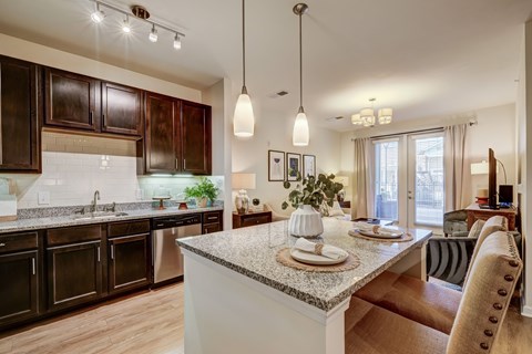 A kitchen with a marble countertop and a dining table set for two.