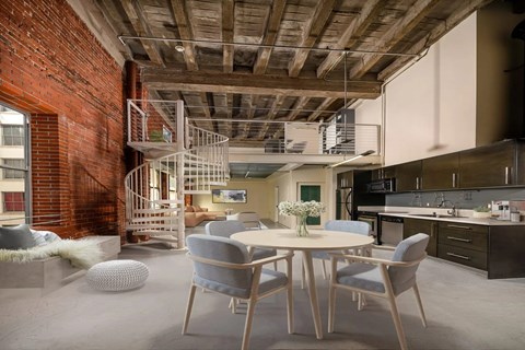 A dining room with a round table and grey chairs.