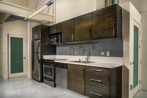 A modern kitchen with dark wood cabinets and stainless steel appliances.