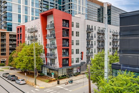 A modern red and white building is in the foreground of a street scene.