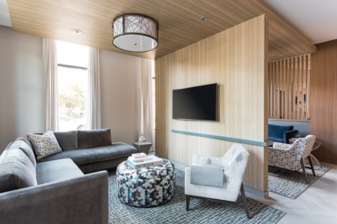 A modern living room with a grey couch, a black TV, and a wooden wall.