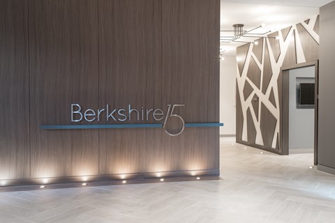 A modern office lobby with a wooden wall and a sign that reads "Berkshire.".