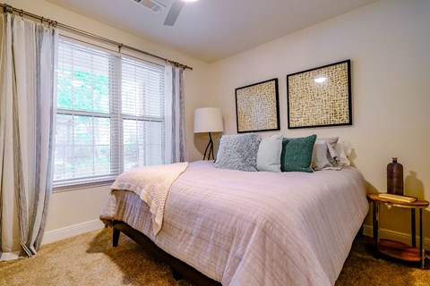 A bedroom with a bed, a nightstand, and a window with curtains.