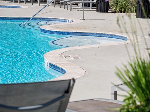 A pool with a chair and a table nearby.