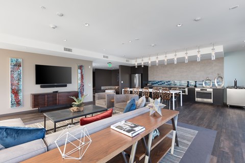 A modern living room with a glass table and a TV on the wall.