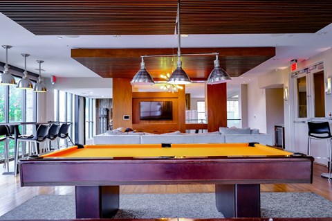 A pool table is in the middle of a room with a TV and a couch.